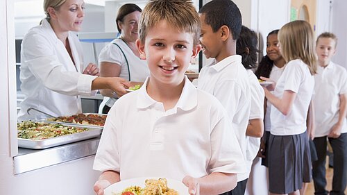 A boy holding a plate of food after leaving the dinner line.